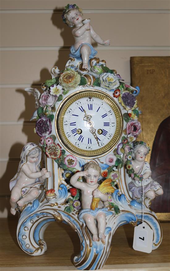 A late 19th century Thuringian porcelain mantel clock, encrusted with flowers, mounted with cherubs (some faults)